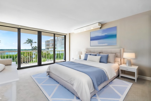 bedroom featuring multiple windows, access to outside, expansive windows, and a water view