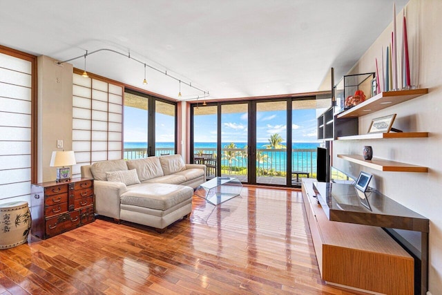 living room featuring french doors, track lighting, floor to ceiling windows, wood-type flooring, and a water view