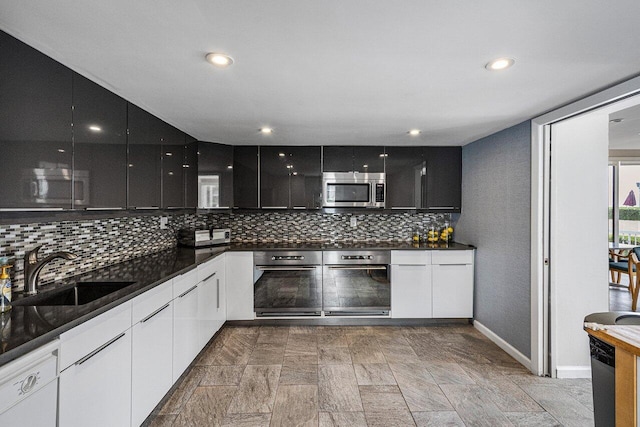 kitchen with stainless steel appliances, white cabinetry, tasteful backsplash, and sink