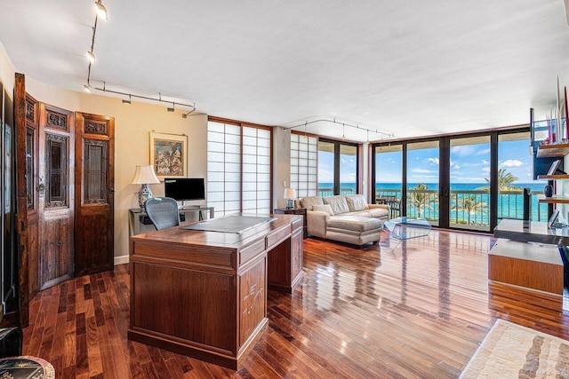 office area with floor to ceiling windows and dark wood-type flooring