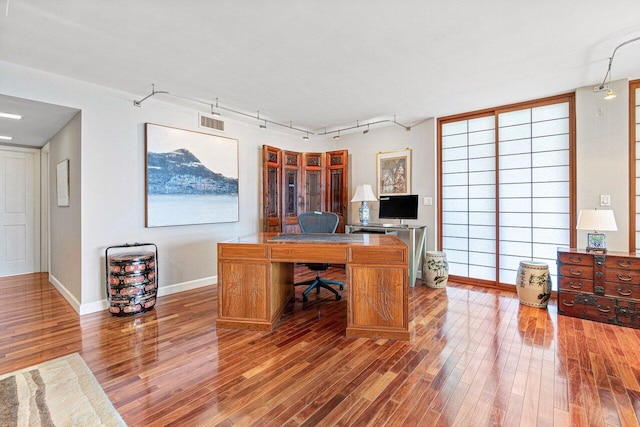 home office with hardwood / wood-style floors and track lighting