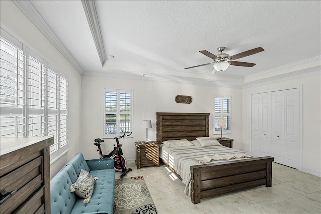 bedroom featuring ornamental molding, a textured ceiling, a raised ceiling, ceiling fan, and a closet