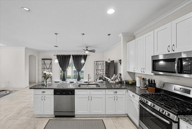 kitchen with sink, kitchen peninsula, pendant lighting, white cabinets, and appliances with stainless steel finishes