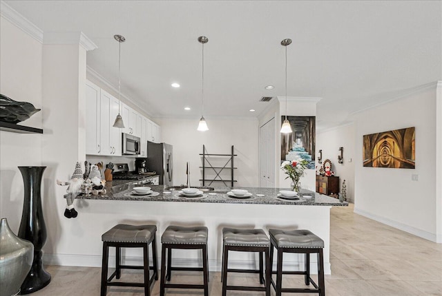 kitchen featuring dark stone countertops, ornamental molding, appliances with stainless steel finishes, white cabinetry, and kitchen peninsula