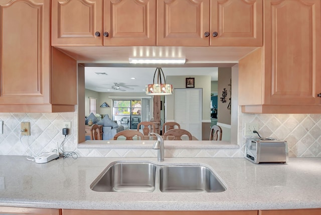 kitchen featuring ceiling fan, light stone countertops, sink, and tasteful backsplash