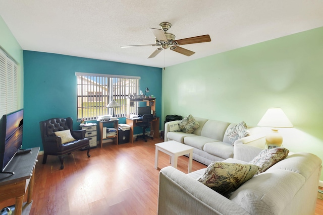 living room featuring hardwood / wood-style flooring, ceiling fan, and a textured ceiling