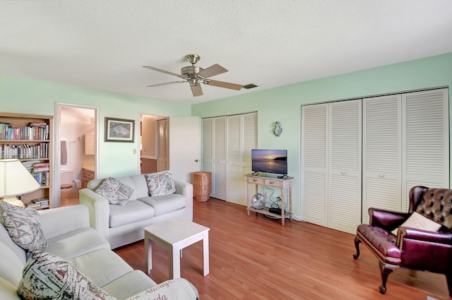 living room with hardwood / wood-style floors, ceiling fan, and a textured ceiling