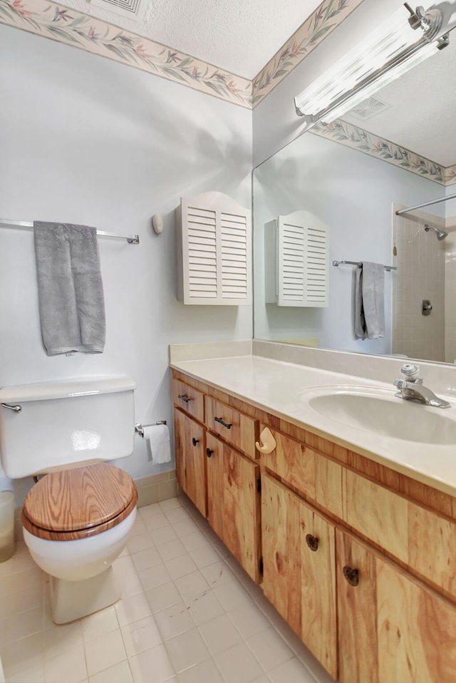 bathroom featuring vanity, tile patterned flooring, toilet, a textured ceiling, and a tile shower