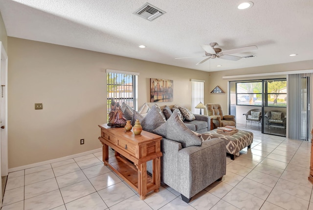 living room featuring ceiling fan, light tile patterned floors, and a textured ceiling