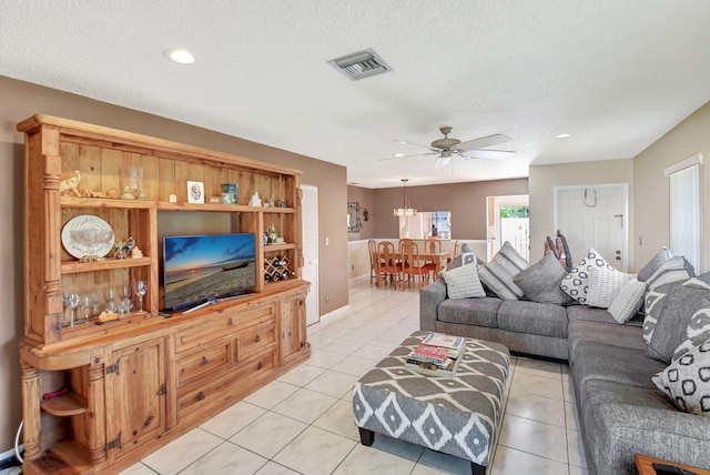 living room with ceiling fan, light tile patterned flooring, and a textured ceiling