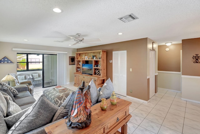 tiled living room with ceiling fan and a textured ceiling