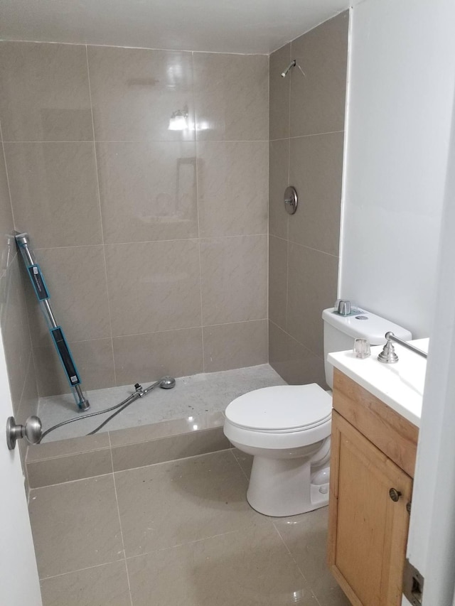 bathroom with tiled shower, vanity, toilet, and tile patterned flooring