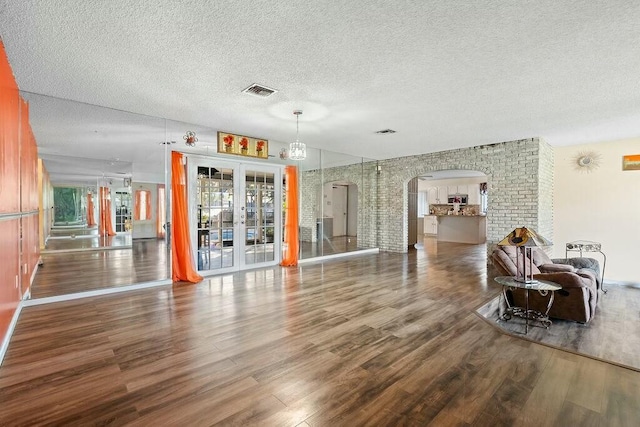 living room with french doors, a textured ceiling, and dark hardwood / wood-style floors