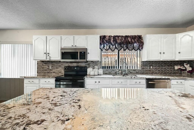 kitchen featuring light stone counters, sink, white cabinets, and appliances with stainless steel finishes