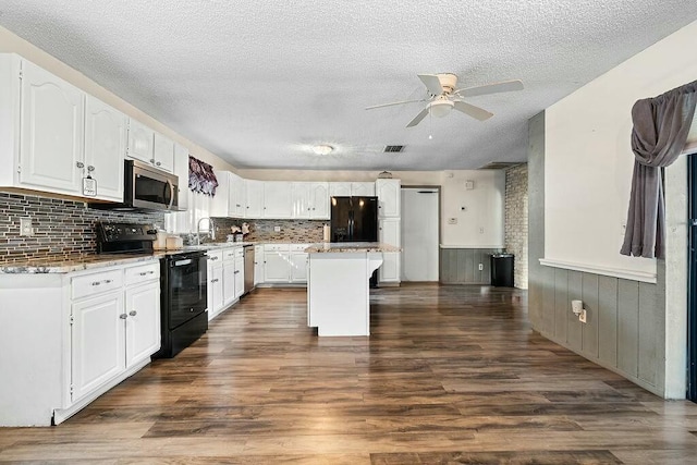 kitchen featuring white cabinetry, a kitchen island, dark wood-type flooring, and black appliances