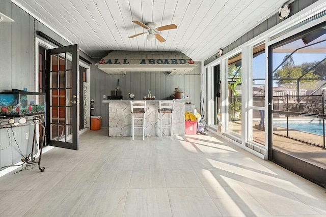 view of patio with ceiling fan, a lanai, and a bar