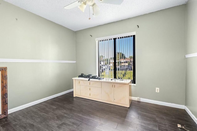 unfurnished office with ceiling fan, dark hardwood / wood-style flooring, and a textured ceiling