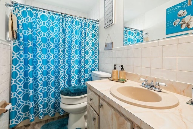 bathroom with backsplash, vanity, toilet, and tile walls