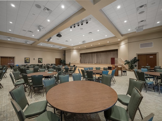 carpeted dining room with a drop ceiling and a high ceiling