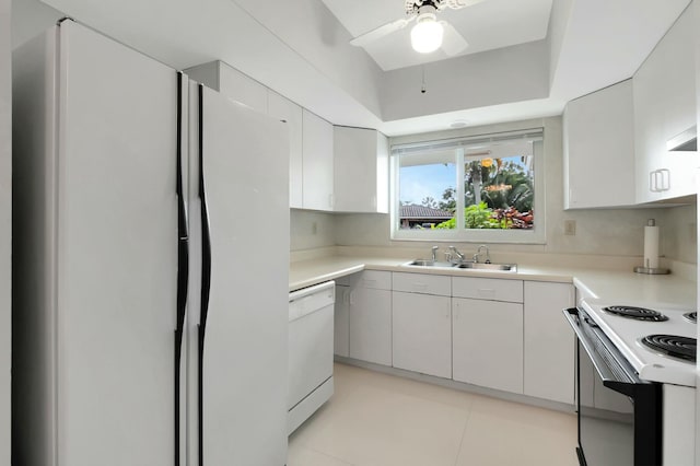 kitchen featuring white appliances, a raised ceiling, ceiling fan, sink, and white cabinets