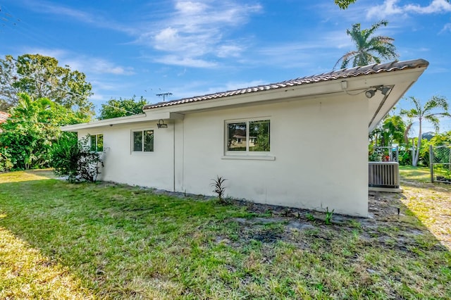 view of side of property featuring a yard and central AC unit