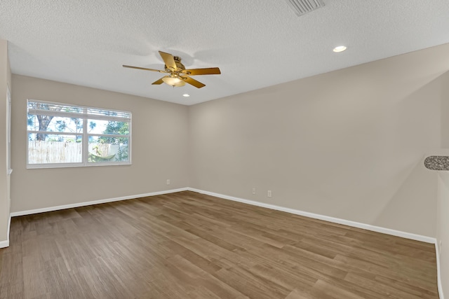 spare room with a textured ceiling, hardwood / wood-style flooring, and ceiling fan