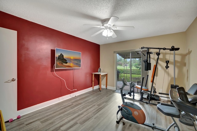 workout area with ceiling fan, wood-type flooring, and a textured ceiling