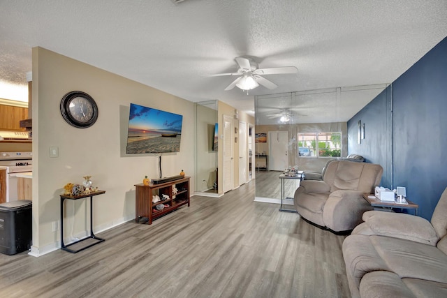 living room featuring ceiling fan, a textured ceiling, and light hardwood / wood-style flooring