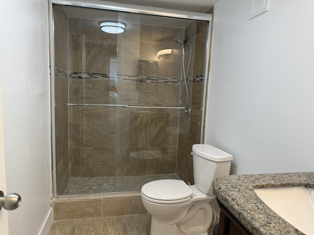 bathroom featuring toilet, a shower with door, and vanity