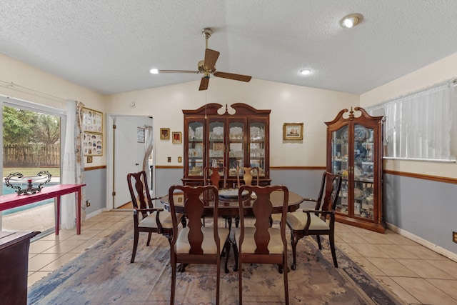 tiled dining room featuring a textured ceiling, vaulted ceiling, and ceiling fan