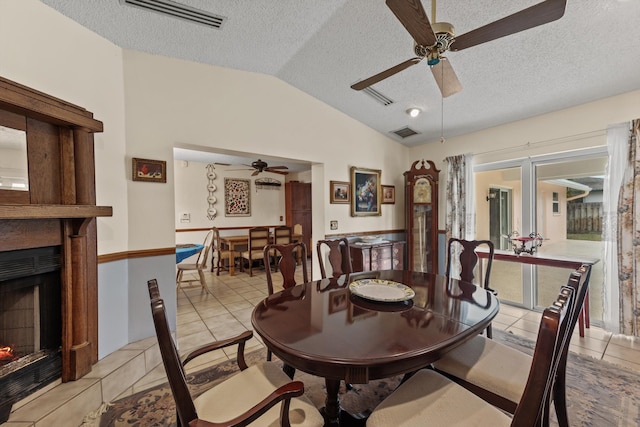 tiled dining area with a textured ceiling, ceiling fan, and lofted ceiling