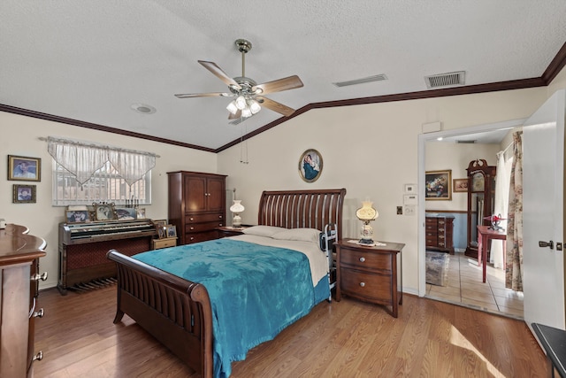 bedroom featuring ceiling fan, light wood-type flooring, lofted ceiling, and a textured ceiling