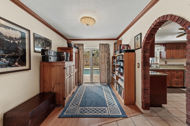 tiled foyer featuring a textured ceiling, ornamental molding, and sink