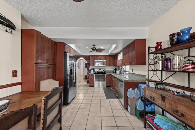 kitchen with a raised ceiling, sink, ceiling fan, light tile patterned floors, and stainless steel appliances