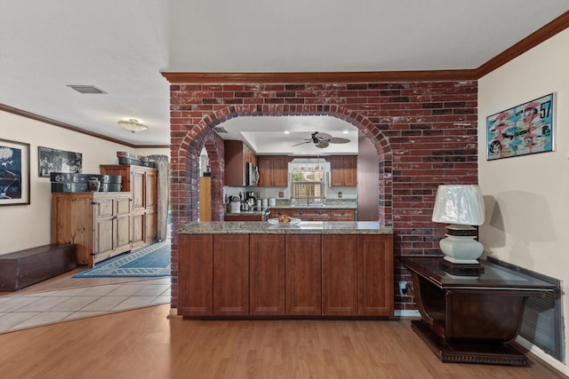 kitchen featuring light stone countertops, ceiling fan, light hardwood / wood-style flooring, kitchen peninsula, and ornamental molding