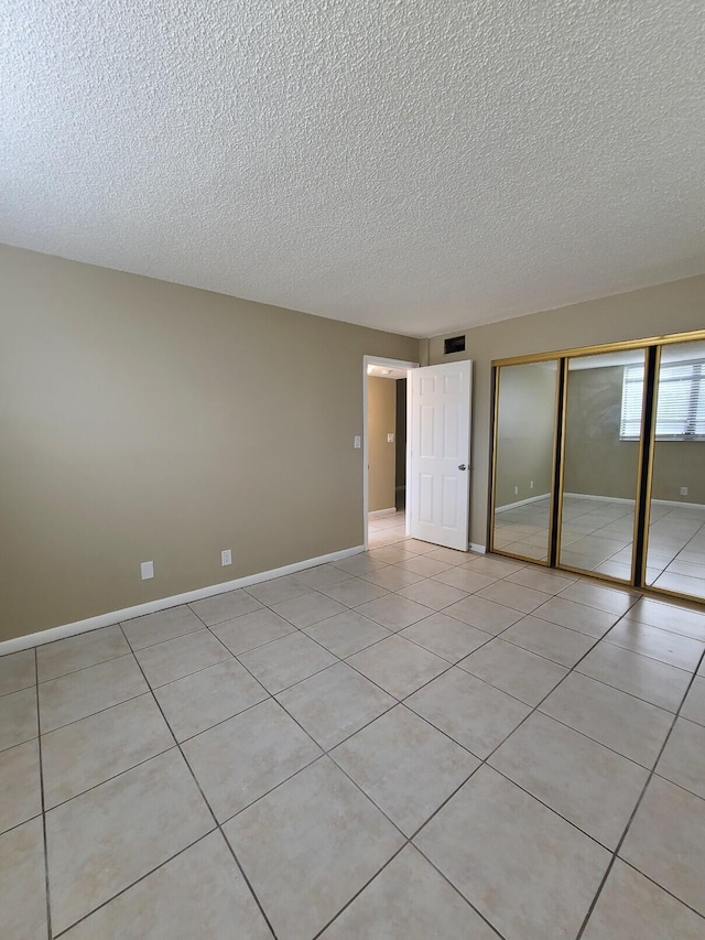 unfurnished bedroom with light tile patterned floors, a textured ceiling, and a closet