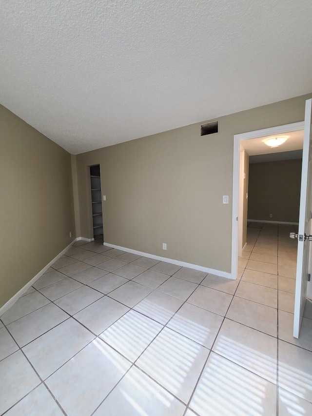 tiled spare room with a textured ceiling