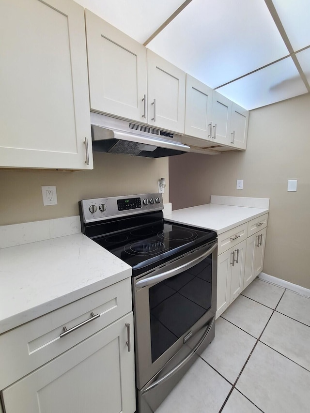 kitchen with stainless steel electric stove, white cabinetry, and light tile patterned floors