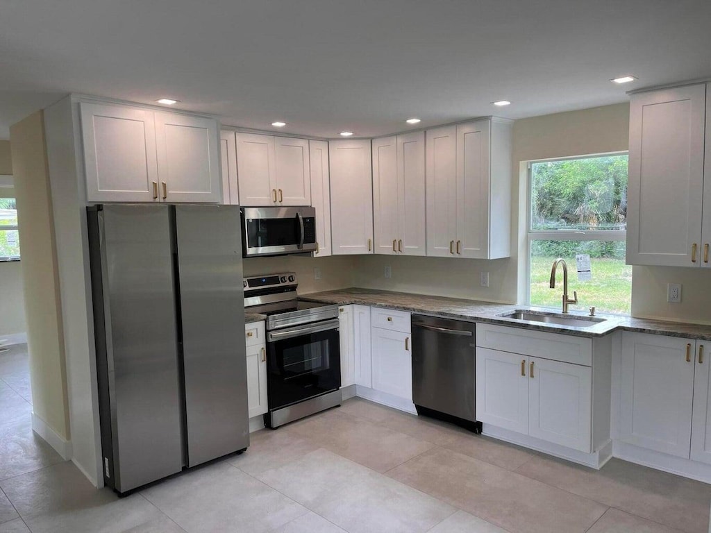 kitchen featuring light tile patterned flooring, stainless steel appliances, white cabinetry, and sink