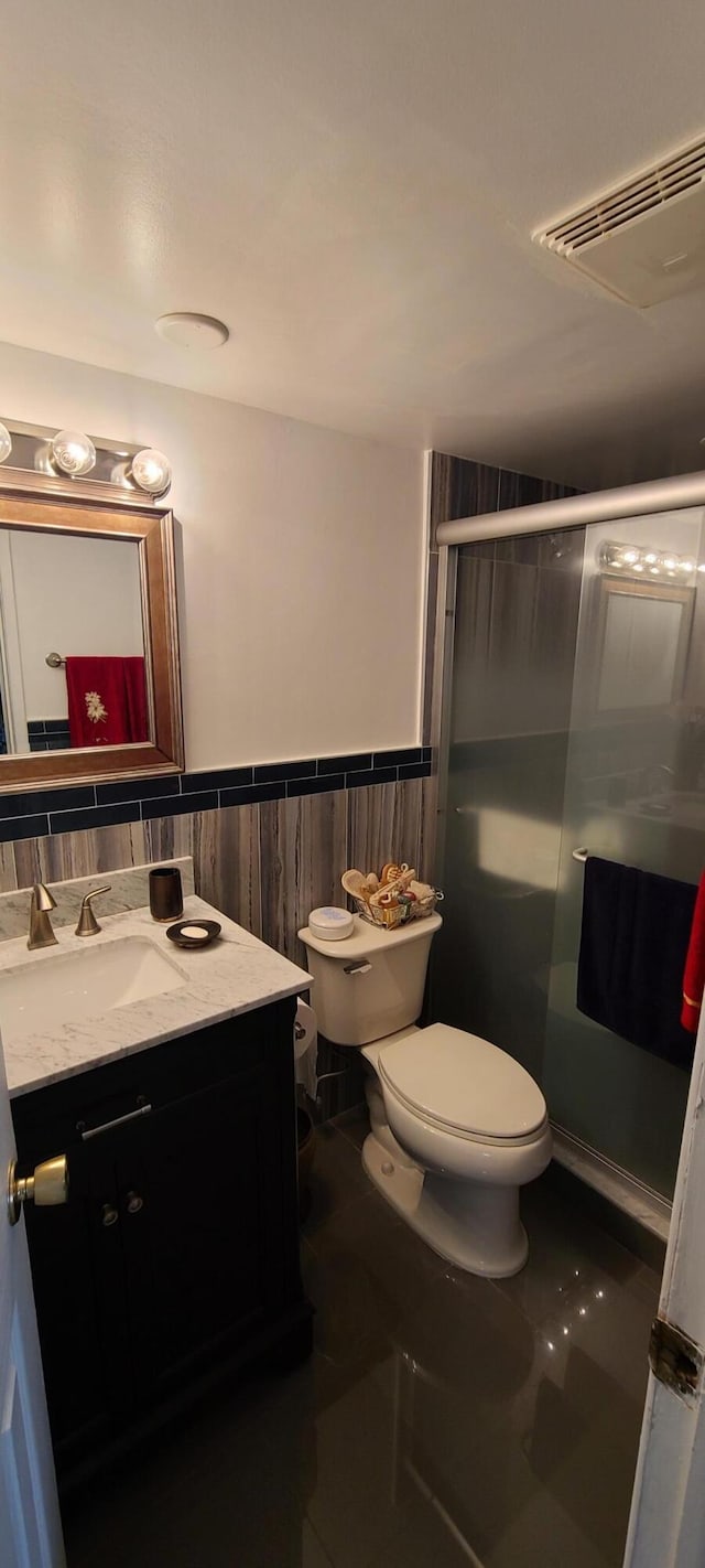 bathroom with tile patterned floors, walk in shower, vanity, and toilet