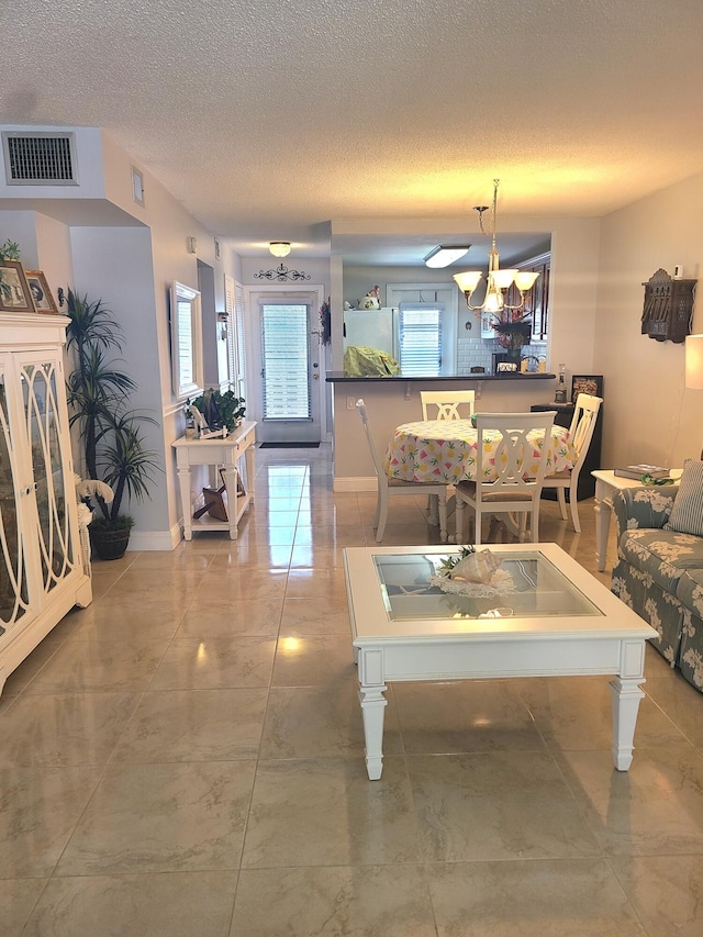 living area featuring visible vents, baseboards, and a textured ceiling