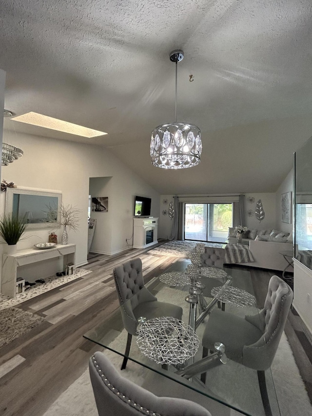 dining space featuring vaulted ceiling with skylight, wood-type flooring, and a textured ceiling