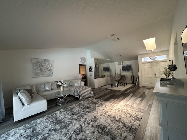 living room with vaulted ceiling with skylight, hardwood / wood-style floors, and a textured ceiling