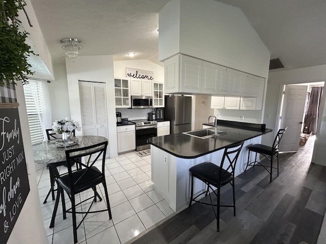 kitchen with a breakfast bar, white cabinetry, sink, and appliances with stainless steel finishes