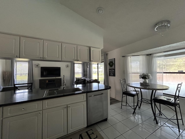 kitchen featuring dishwasher, lofted ceiling, white cabinets, sink, and light tile patterned floors