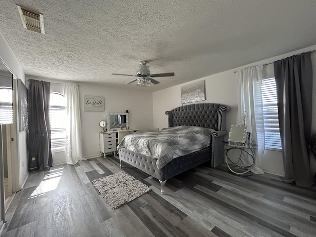 bedroom with hardwood / wood-style floors, ceiling fan, and a textured ceiling