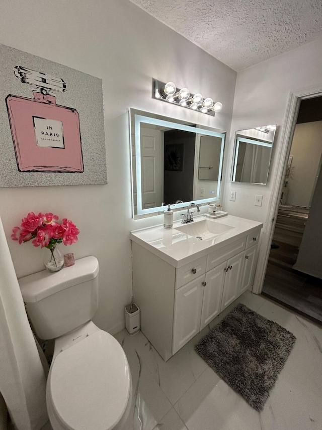 bathroom with vanity, toilet, and a textured ceiling