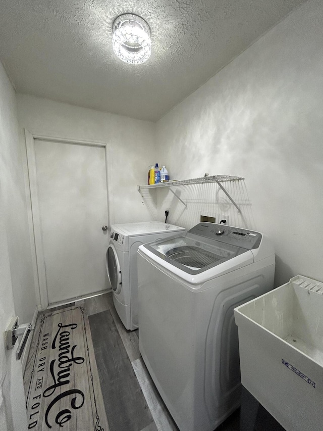 washroom with a textured ceiling, wood-type flooring, independent washer and dryer, and sink