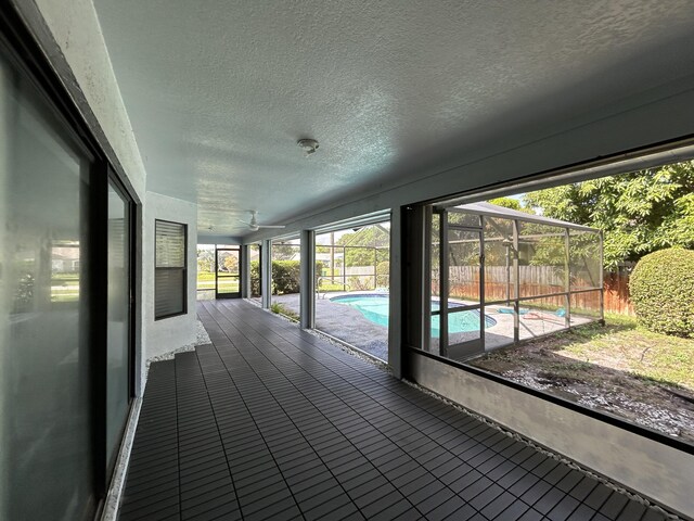 wooden terrace with a fenced in pool, glass enclosure, and a patio