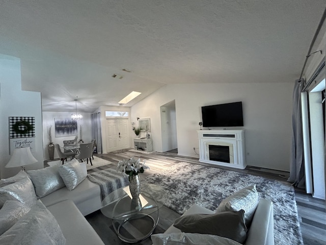 living room featuring hardwood / wood-style floors, vaulted ceiling, and an inviting chandelier